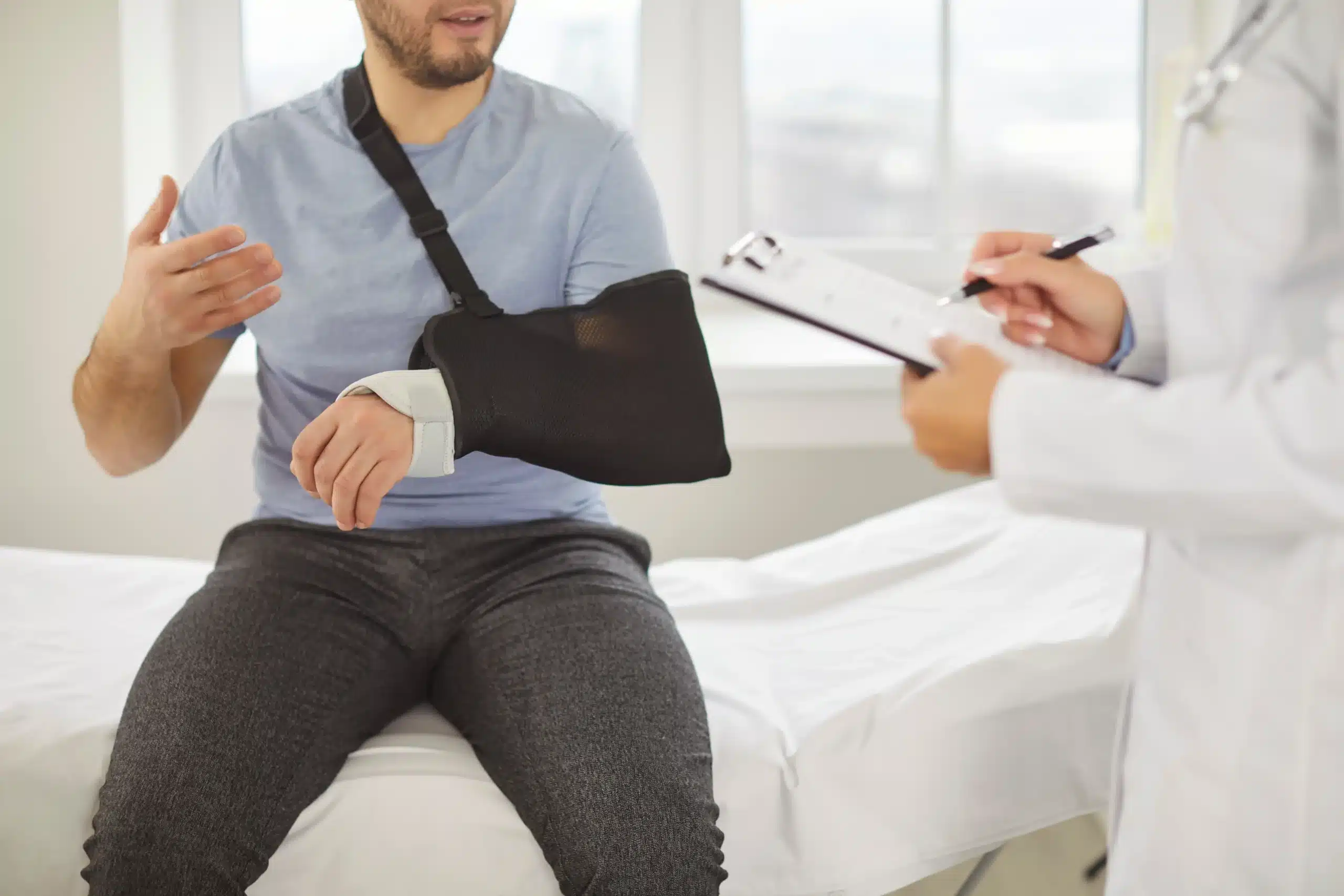 Injured worker wearing arm sling consulting with doctor during independent medical exam for workers’ compensation in New York.