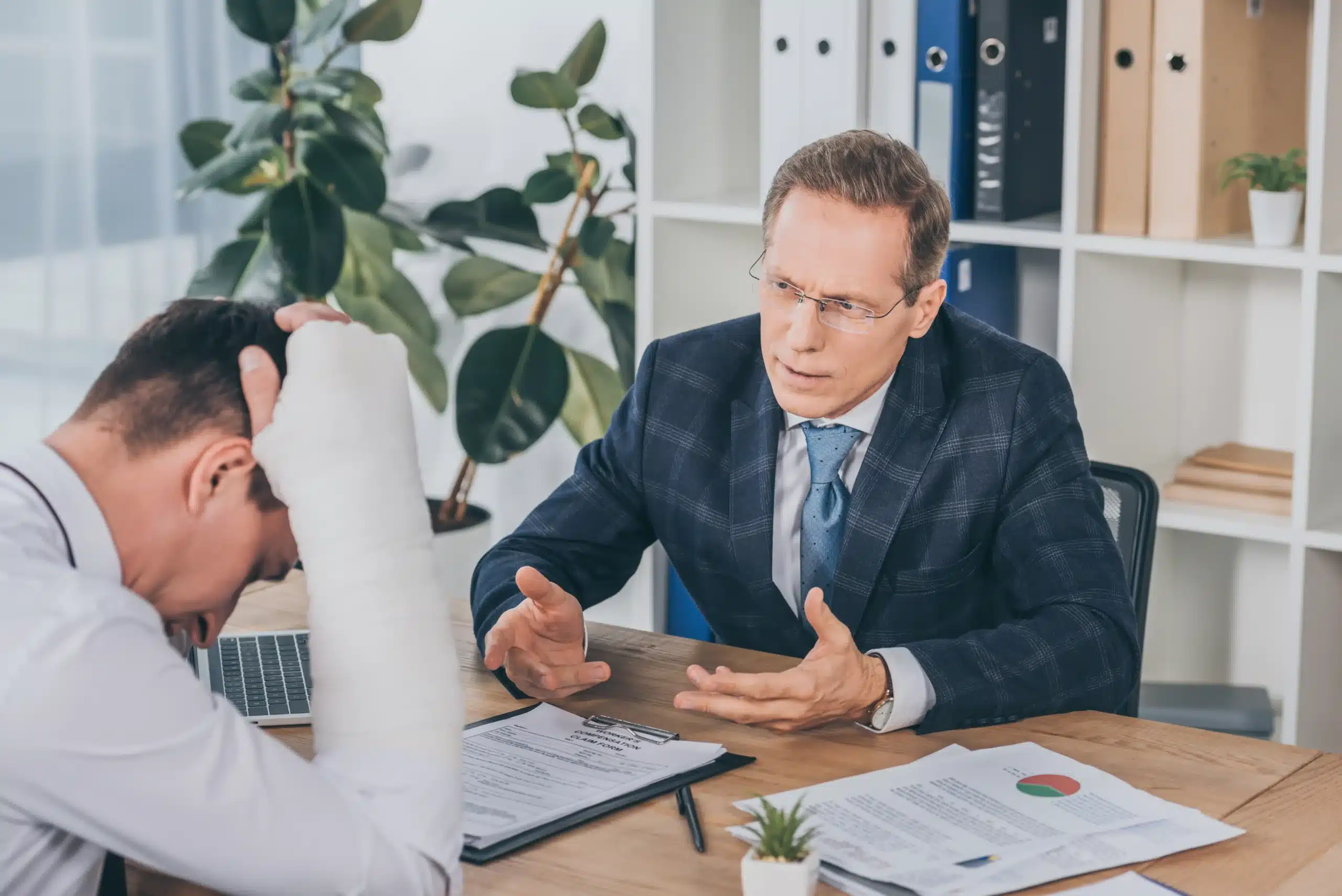 Injured worker with broken arm reviewing settlement documents with attorney in New York office, discussing workers’ compensation and SSDI benefits.