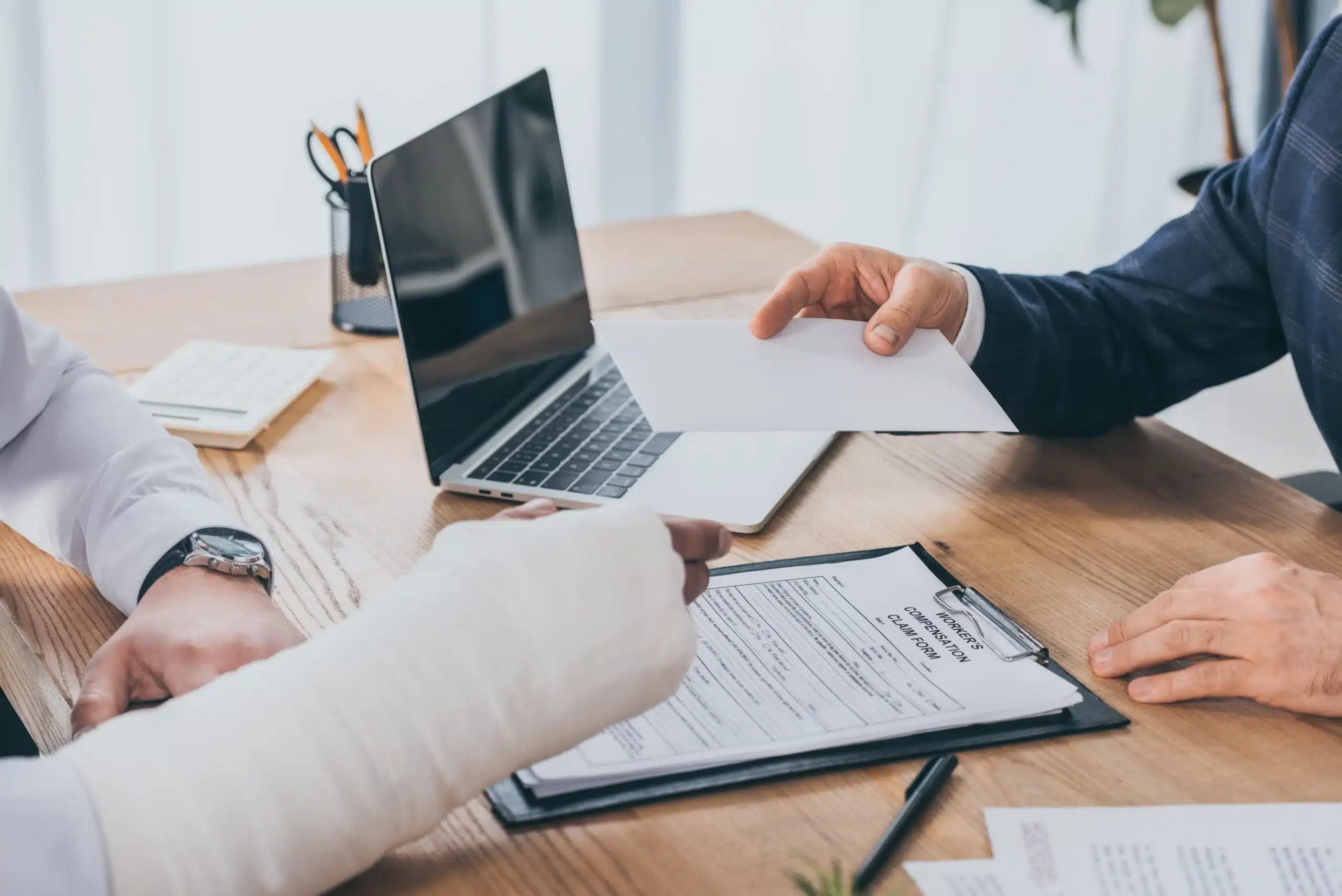 Businessman handing a compensation document to an injured worker with a broken arm, representing workers’ compensation and Social Security disability in New York.